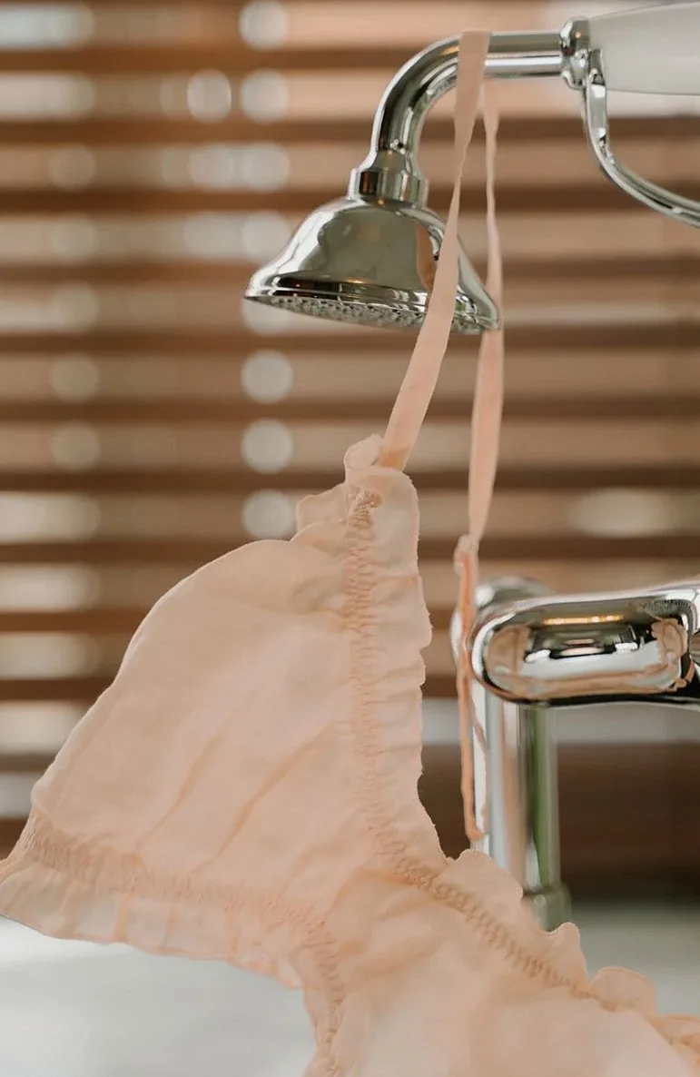 Elegant close-up of a delicate brassiere hanging on a faucet with warm lighting.
